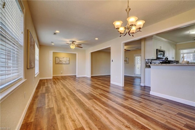 unfurnished living room with light hardwood / wood-style flooring and ceiling fan with notable chandelier