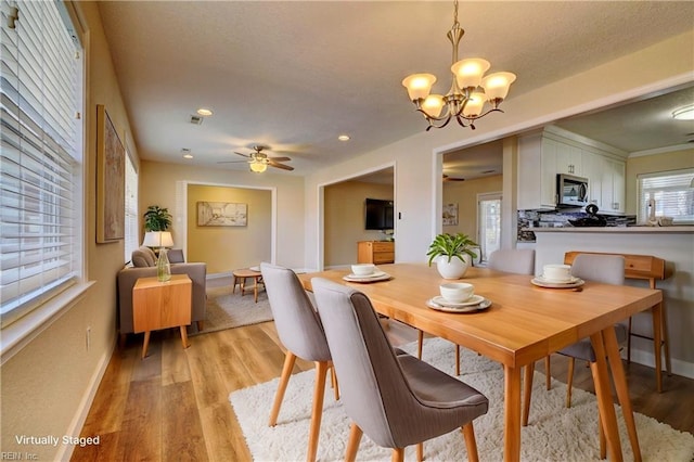 dining area featuring light hardwood / wood-style floors and ceiling fan with notable chandelier