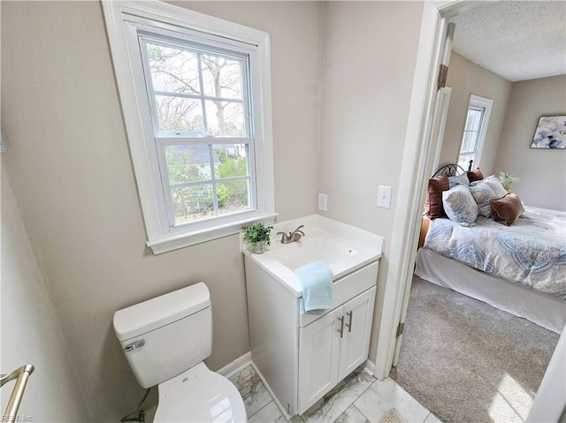 bathroom featuring toilet, vanity, plenty of natural light, and a textured ceiling