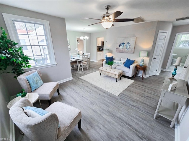 living room featuring dark wood-type flooring and ceiling fan with notable chandelier