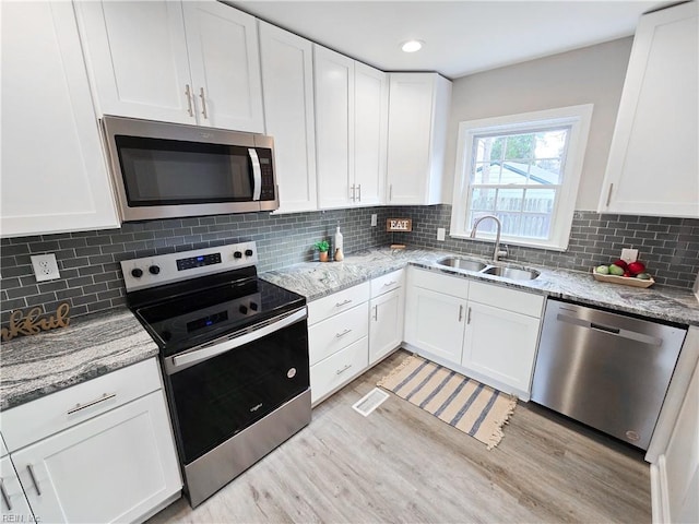 kitchen with white cabinets, light stone countertops, sink, and stainless steel appliances