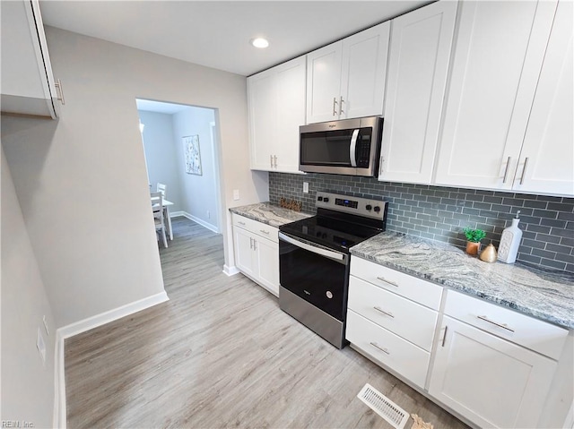 kitchen with white cabinets, backsplash, appliances with stainless steel finishes, and light stone counters