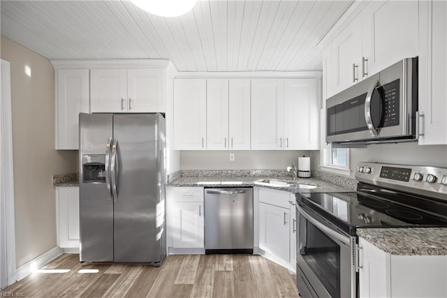 kitchen with appliances with stainless steel finishes, sink, white cabinetry, and light stone counters