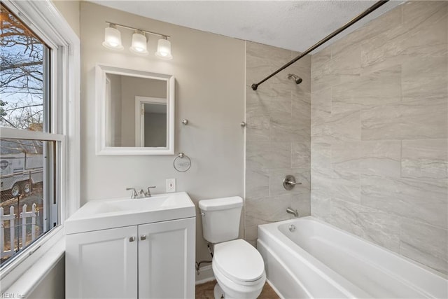 full bathroom featuring a textured ceiling, vanity, tiled shower / bath combo, and toilet