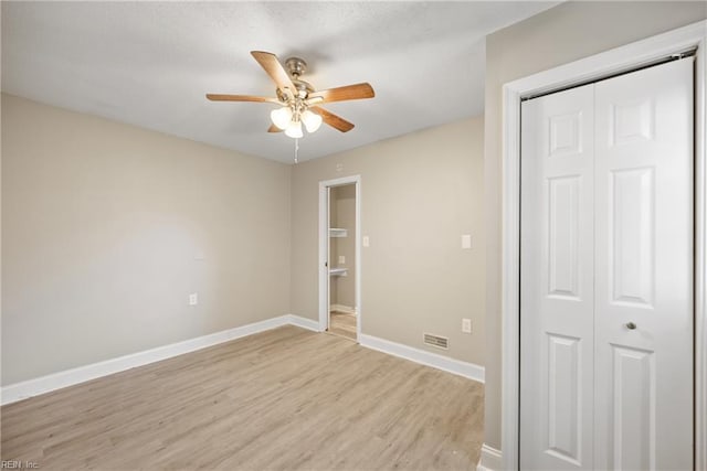 unfurnished bedroom featuring ceiling fan, light hardwood / wood-style floors, and a closet