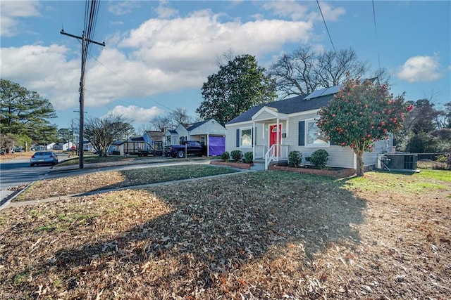 view of front of property featuring cooling unit, a front yard, and solar panels