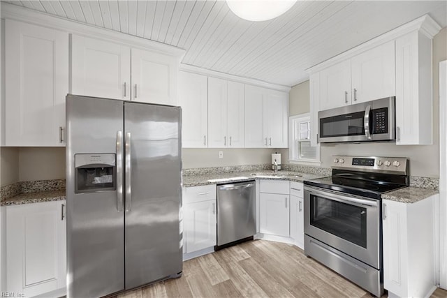 kitchen with light stone counters, light hardwood / wood-style flooring, white cabinets, and appliances with stainless steel finishes