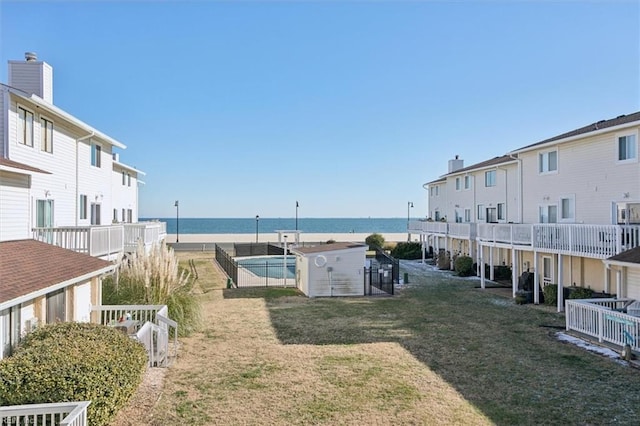 view of yard featuring a pool, a storage shed, and a water view