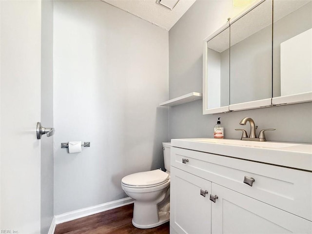 bathroom with a textured ceiling, hardwood / wood-style floors, vanity, and toilet