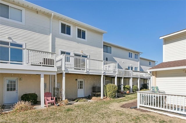 rear view of property featuring central air condition unit, a lawn, and a wooden deck