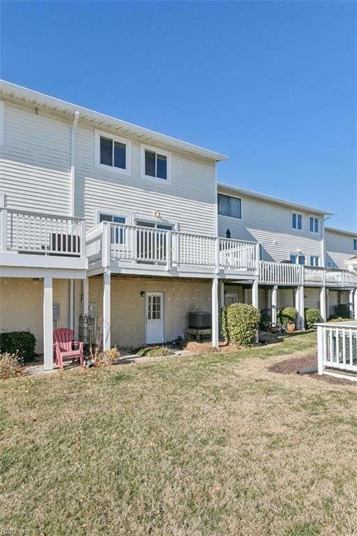 rear view of house featuring central air condition unit, a lawn, and a wooden deck