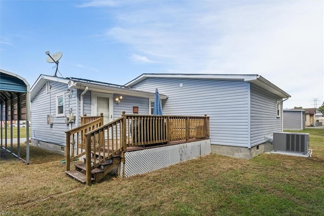 rear view of house with central air condition unit, a lawn, and a carport