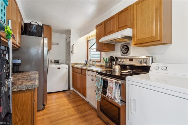 kitchen with sink, washer and dryer, ornamental molding, light wood-type flooring, and stainless steel appliances