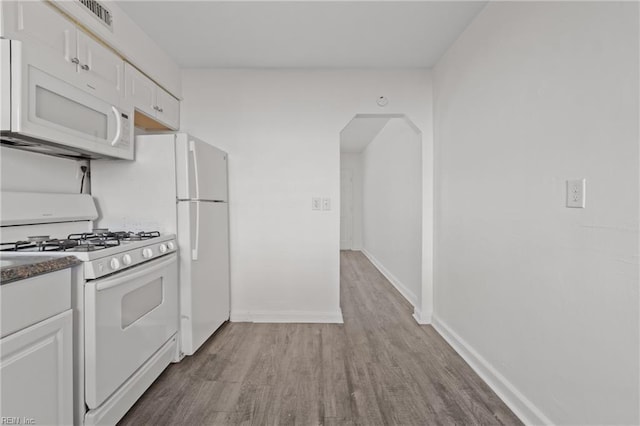 kitchen with white appliances, white cabinets, and light wood-type flooring