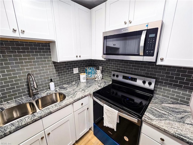 kitchen with backsplash, white cabinets, and electric stove