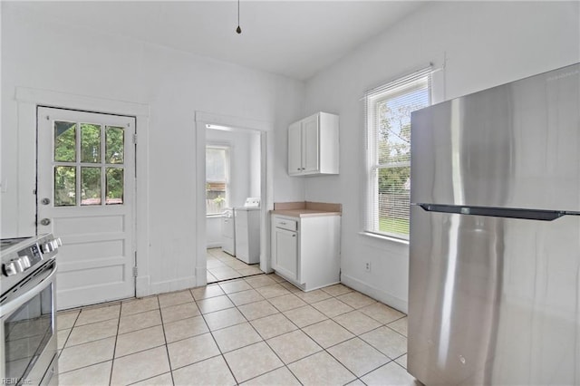 kitchen with stainless steel appliances, light tile patterned floors, washer and dryer, and white cabinets