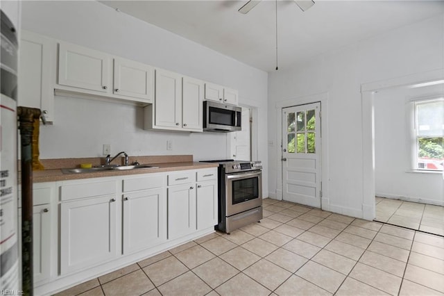 kitchen featuring white cabinets, appliances with stainless steel finishes, light tile patterned floors, and sink