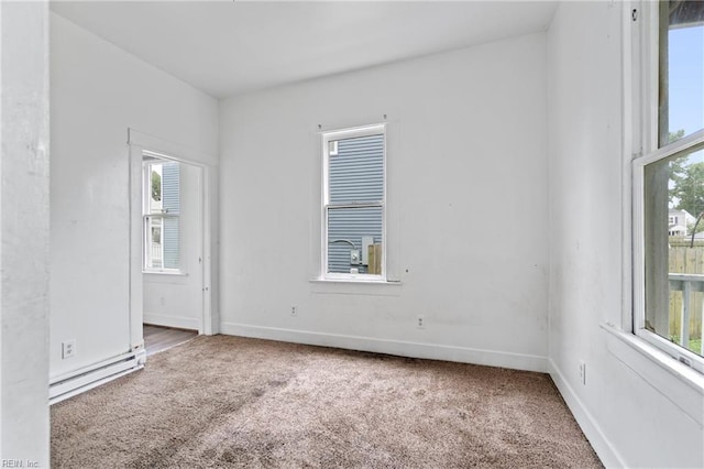 spare room featuring a wealth of natural light, baseboard heating, and carpet