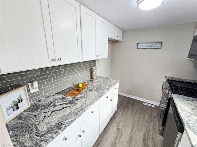 kitchen with white cabinets, light hardwood / wood-style flooring, gas stove, and light stone countertops