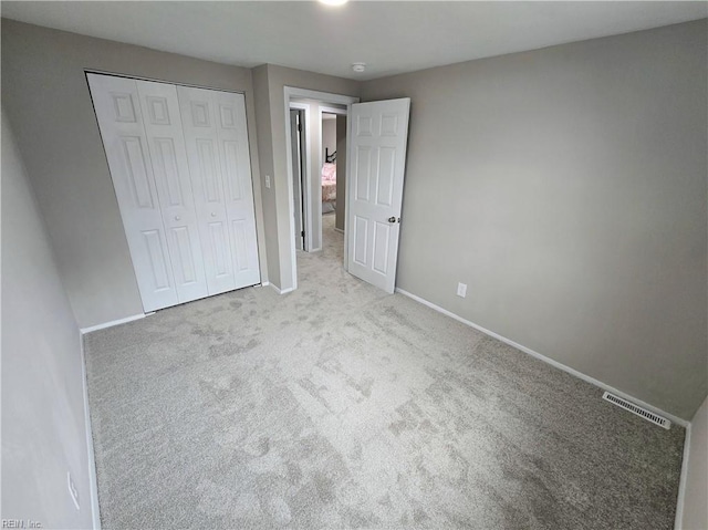 unfurnished bedroom featuring a closet and light colored carpet