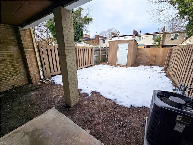 yard layered in snow featuring central air condition unit and a shed