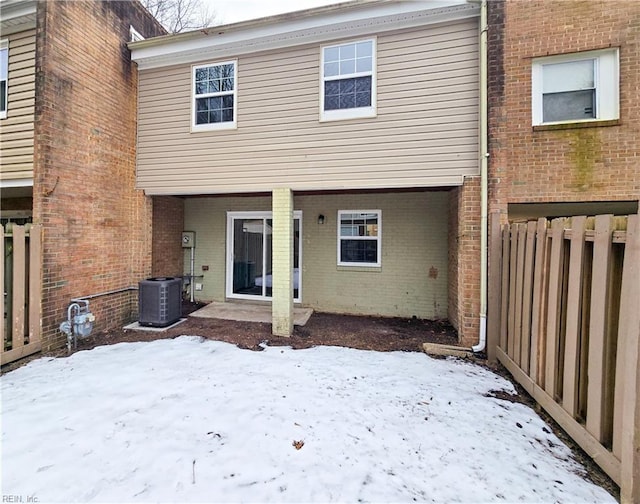 snow covered rear of property featuring central AC unit