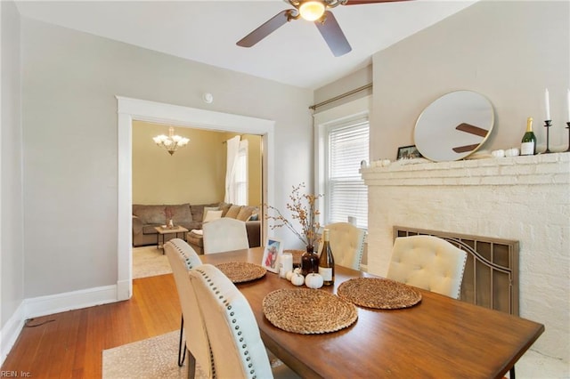 dining room with ceiling fan with notable chandelier and light hardwood / wood-style flooring