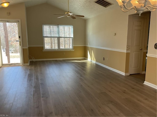 unfurnished room featuring ceiling fan with notable chandelier, dark wood-type flooring, a textured ceiling, and vaulted ceiling