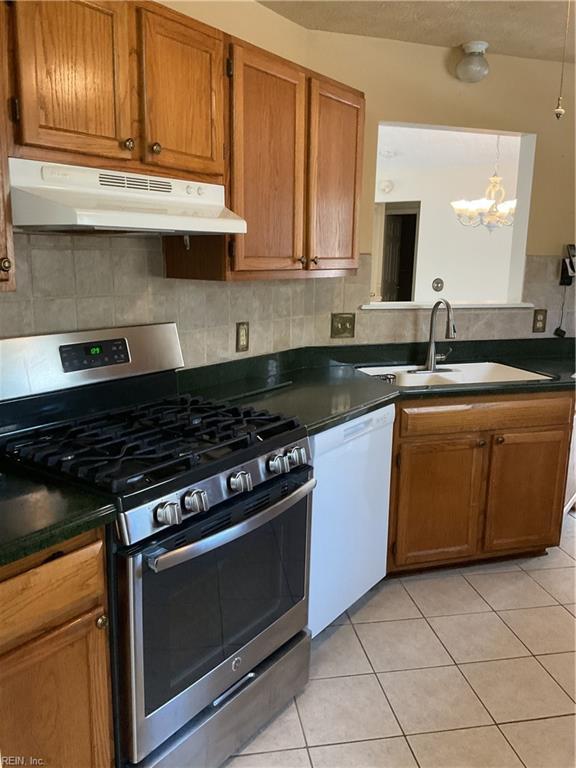 kitchen featuring light tile patterned floors, white dishwasher, a notable chandelier, sink, and gas range