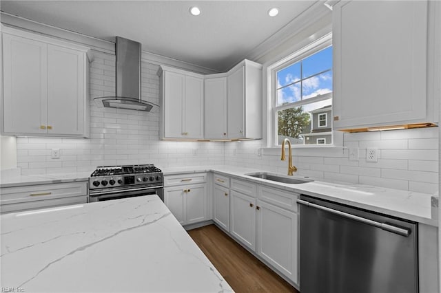 kitchen featuring white cabinetry, wall chimney range hood, stainless steel appliances, sink, and light stone counters