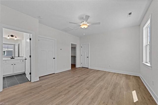 unfurnished bedroom with ceiling fan, connected bathroom, and light hardwood / wood-style flooring