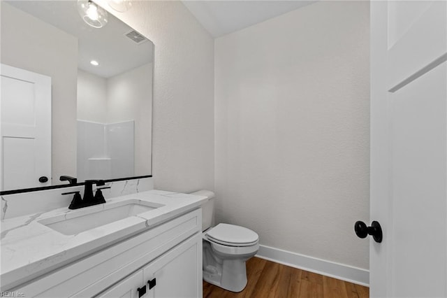 bathroom with hardwood / wood-style flooring, a shower, toilet, and vanity