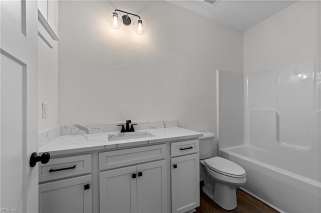 full bathroom with toilet, vanity, wood-type flooring, and washtub / shower combination