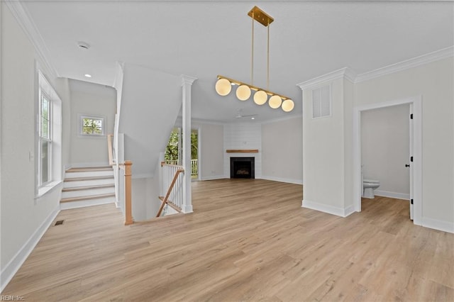 unfurnished living room featuring ornamental molding, light hardwood / wood-style floors, and a large fireplace