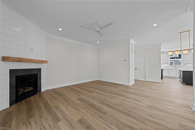 unfurnished living room with light hardwood / wood-style flooring, sink, ornamental molding, ceiling fan, and a tile fireplace