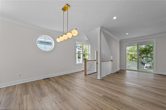 unfurnished living room with light hardwood / wood-style floors, a textured ceiling, and ornamental molding