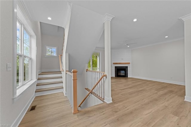 unfurnished living room featuring light hardwood / wood-style floors, a large fireplace, and crown molding