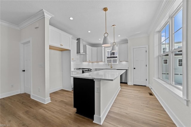 kitchen featuring backsplash, pendant lighting, a center island, white cabinetry, and wall chimney exhaust hood