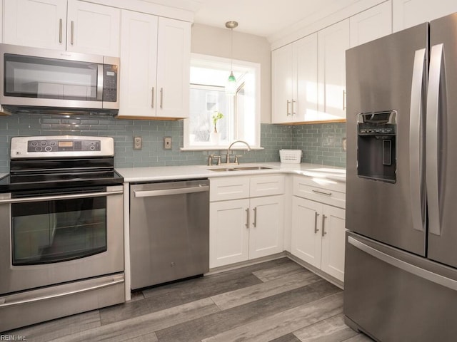 kitchen featuring backsplash, white cabinets, decorative light fixtures, and appliances with stainless steel finishes