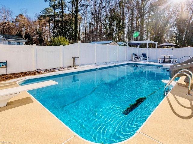 view of swimming pool featuring a diving board and a patio