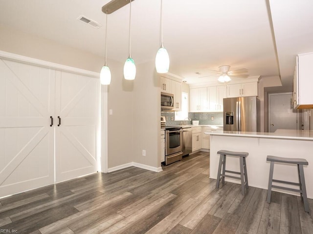 kitchen with white cabinets, ceiling fan, a breakfast bar, and appliances with stainless steel finishes