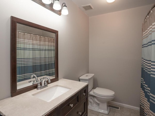 bathroom with toilet, vanity, and tile patterned floors