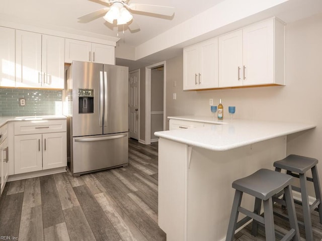 kitchen featuring a breakfast bar, white cabinets, dark hardwood / wood-style floors, tasteful backsplash, and stainless steel fridge with ice dispenser