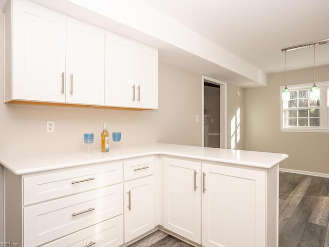 kitchen featuring kitchen peninsula, white cabinets, pendant lighting, and dark hardwood / wood-style floors