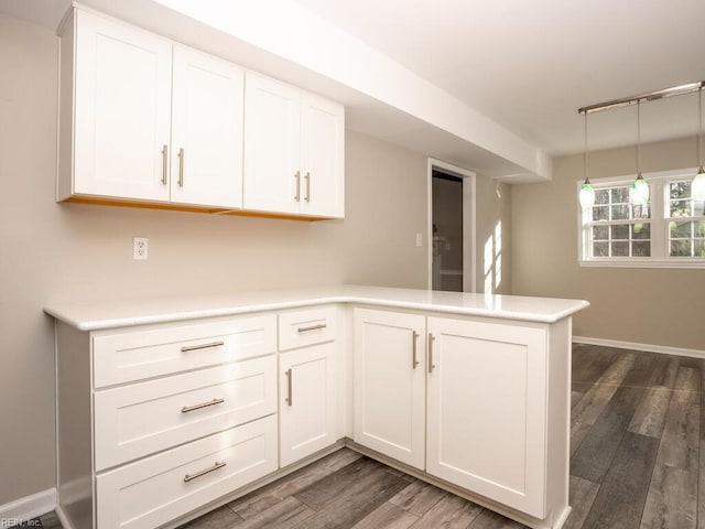 kitchen featuring kitchen peninsula, dark hardwood / wood-style flooring, white cabinets, and pendant lighting