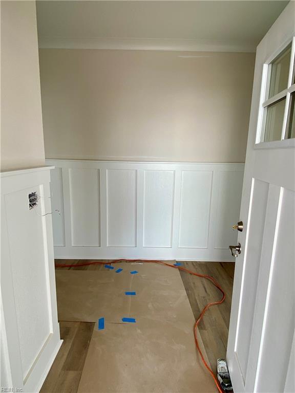 interior space featuring wainscoting, wood finished floors, and a decorative wall