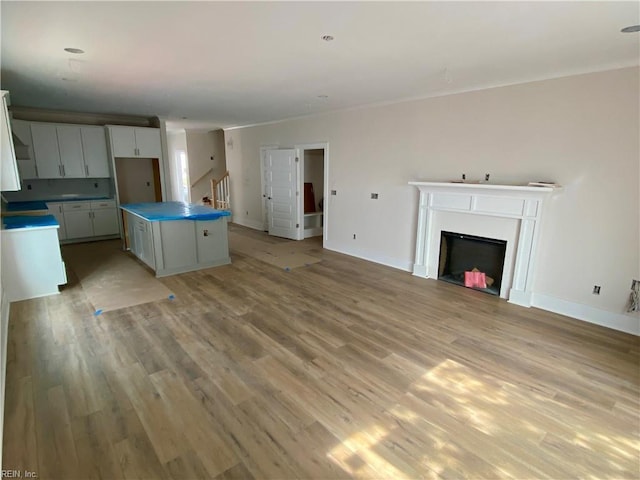 kitchen with baseboards, a fireplace, light wood-style flooring, and a center island