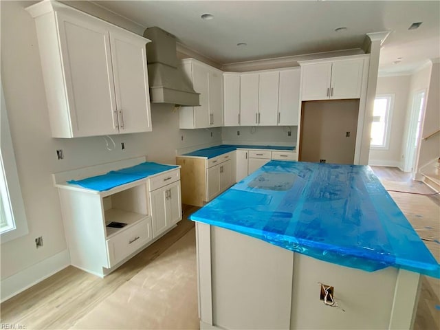 kitchen with light wood finished floors, premium range hood, white cabinets, and a center island