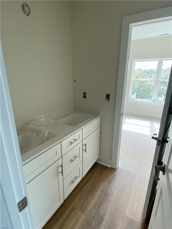 bathroom with double vanity, a sink, baseboards, and wood finished floors