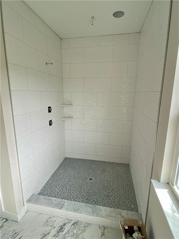 bathroom with marble finish floor and tiled shower